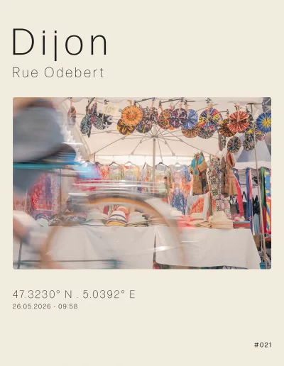 Vue sur un stand de vêtements africains auteur des Halles de Dijon, un jour de marché. Au premier plan, un vélo traverse la scène.