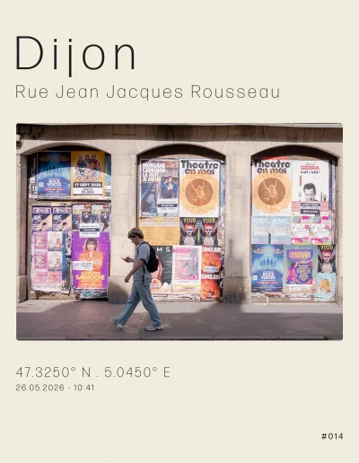 Vue sur un local commercial vide et recouvert d'affiches. Au premier plan, un passant regardant son smartphone traverse la scène.