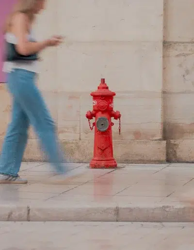 Passante marchant devant une borne incendie rouge dans le centre-ville de Dijon